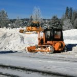 bulldozers push snow away from the railroad tracks