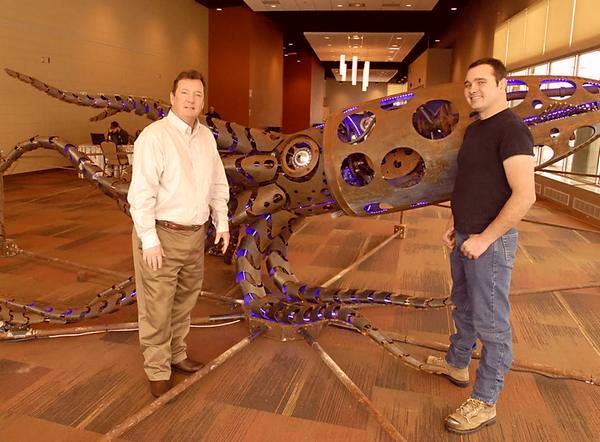 Elko Convention & Visitors Authority Executive Director Don Newman and artist Barry Crawford stand by the installation of Megateuthis at the new Elko Conference Center.